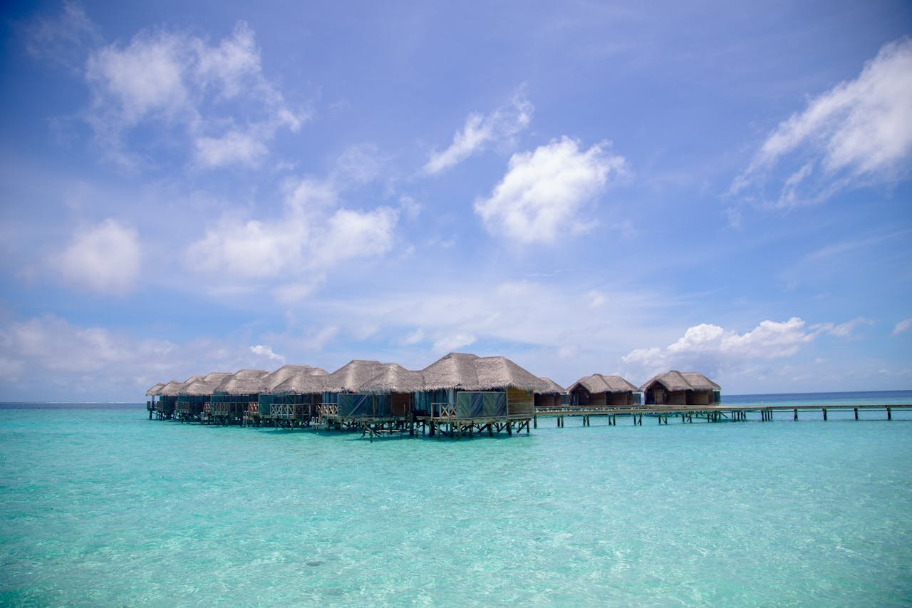 Scenic view of overwater bungalows with a clear blue ocean and sky, perfect for tropical resort escape.
